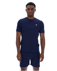Man wearing a navy blue polo shirt and shorts with a FILA logo on a white background