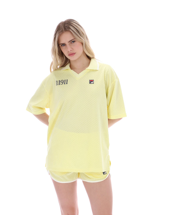 Woman wearing a yellow tennis outfit with a visible brand logo on a white background