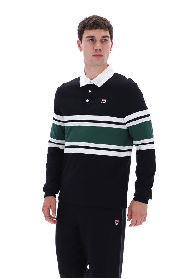 A man wearing a vintage Fila long-sleeve rugby shirt in black with green and white horizontal stripes, paired with black trousers, against a plain white background.