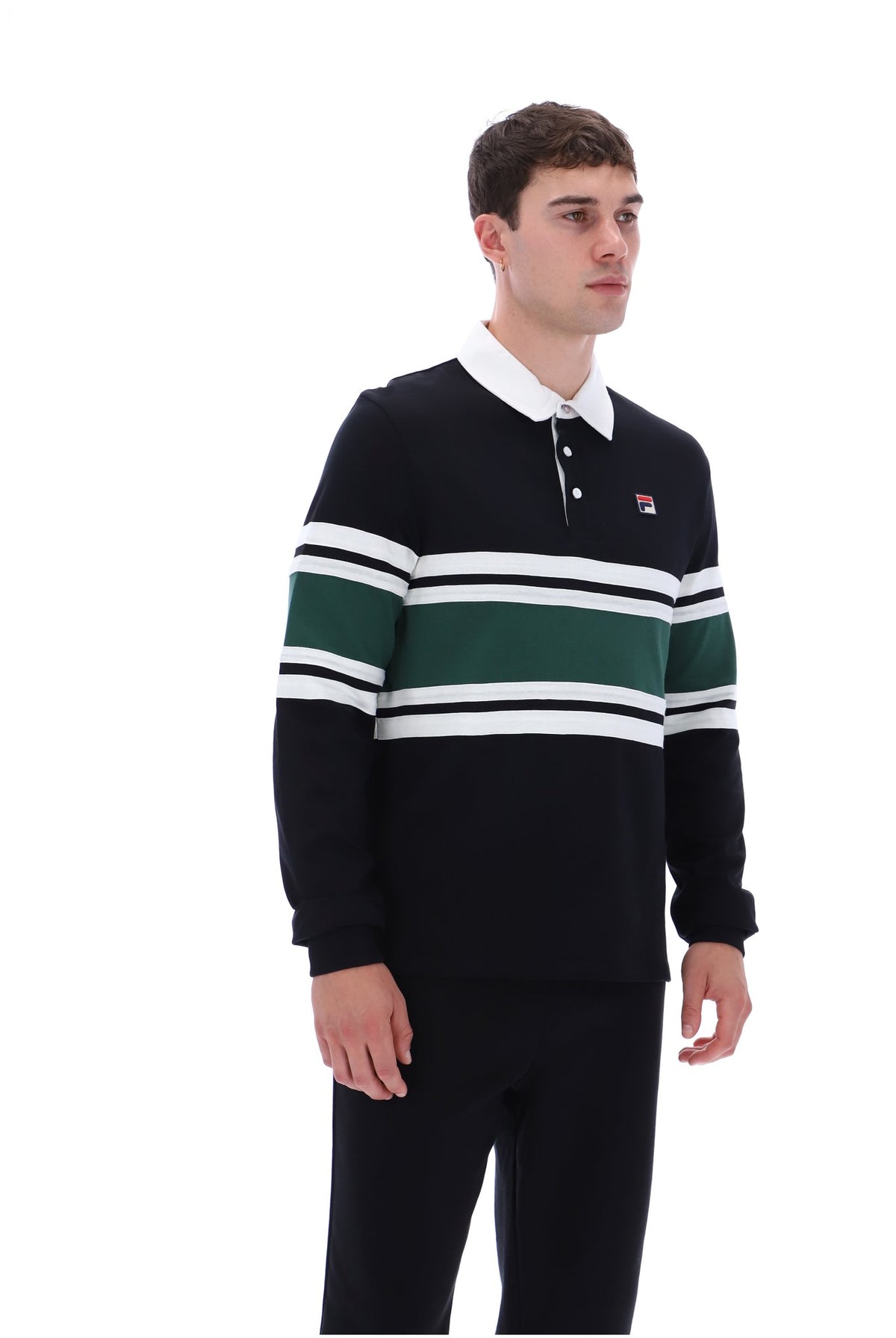 A man wearing a dark navy long-sleeve rugby-style sweater with horizontal white and green stripes across the chest and sleeves, paired with dark pants, photographed against a plain white studio background.