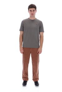 A man modeling a short-sleeve crewneck t-shirt in dark gray with a small embroidered logo on the chest, paired with brown pants and black sneakers, against a plain white background.