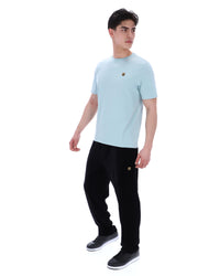 Man wearing a light blue t-shirt and black pants on a white background